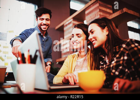 Mitarbeiter, die Lächeln während der Diskussion über laptop Stockfoto