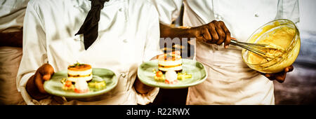 Köchin präsentiert Dessertteller Stockfoto