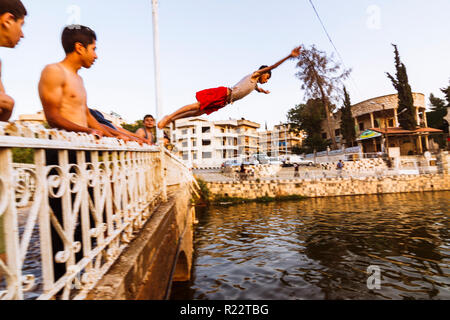 Hama, Hama Governatorat, Syrien: syrische Jugendliche jumpig im Wasser von einem Steg am Orontes. Stockfoto