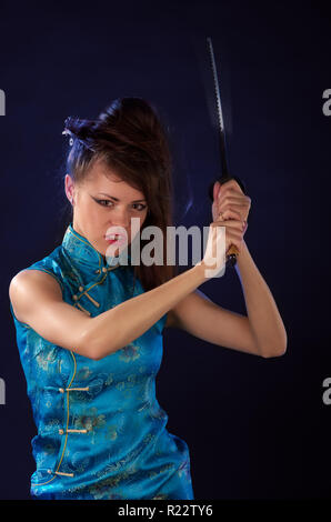 Schöne Mädchen in einem traditionellen Kleid mit Katana in der Hand angezogen Stockfoto