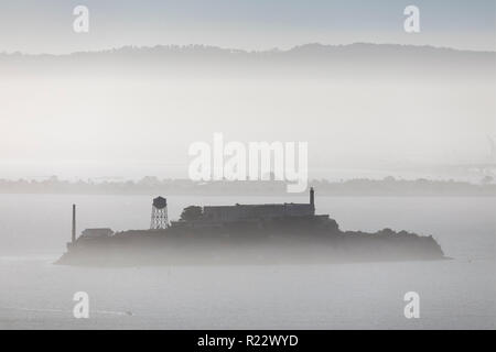 Alcatraz, im berüchtigten Gefängnis von einer Insel mit dem gleichen Namen ist aus der Ferne in einer nebligen San Francisco Bay gesehen. Stockfoto