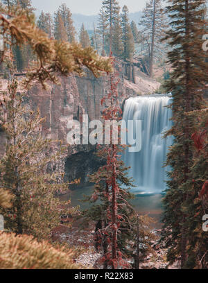 Lange Exposition von Rainbow Falls Wasserfall in Mammoth Lakes, California, USA in der Nähe von Devil's Postpile. Hohe Klippen, die umliegenden Bäume, und blauer Himmel. Rainb Stockfoto