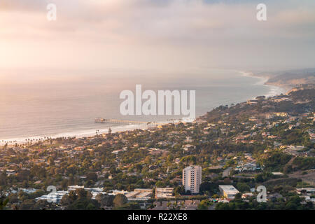 Landschaft der Küste Blick auf La Jolla, San Diego, Kalifornien, USA bei Sonnenuntergang mit Scripps Pier und ein etwas bewölkt, Sonnenuntergang. Gebäude, Palmen und oce Stockfoto