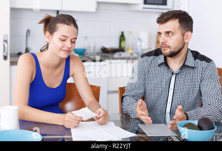 Portrait von umgekippt junges Paar mit Bill in Konflikt in Home Interior Stockfoto