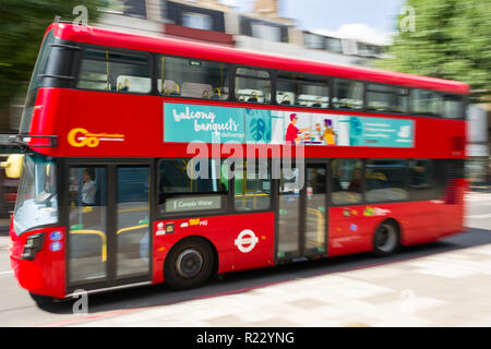 Panning Bild von einem roten Doppeldeckerbus, wie es entlang einer Straße in London an einem sonnigen Tag, London reisen, Großbritannien Stockfoto