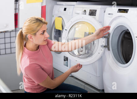 Positive Hausfrau wählt Waschmaschine im Shop von Haushaltsgeräten Stockfoto