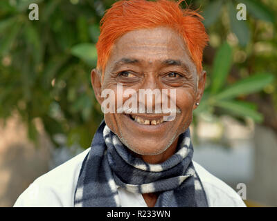 Schielen, im mittleren Alter Inder (rechtes Auge wich nach außen mit einem Bleistift) Schnurrbart und Henna gefärbt orange Haar, Lächeln für die Kamera. Stockfoto