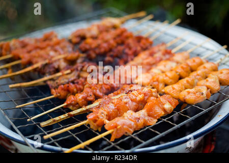 Frischen asiatischen pikante Huhn und Schwein am Spieß Grillen auf dem lokalen Markt. Traditionelle thailändische Küche aus frischen Zutaten. Stockfoto