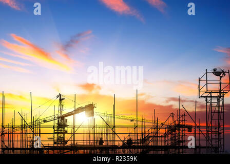 Industriebau-Krane und Gebäude Silhouetten über Sonne bei Sonnenaufgang. Stockfoto