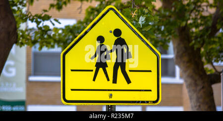Schule zone Schild mit Bäumen und Gebäuden Stockfoto