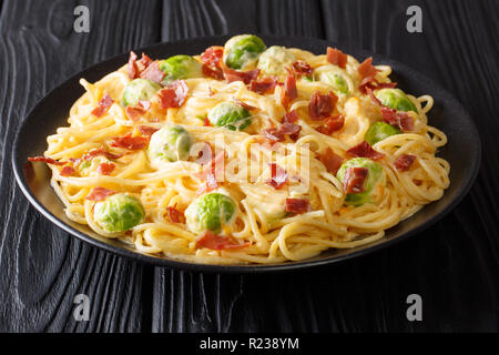 Pikante Spaghetti mit Rosenkohl, Speck, Knoblauch mit geschmolzenem cremige Käse in der Nähe gekocht - bis auf einen Teller auf dem Tisch. Horizontale Stockfoto