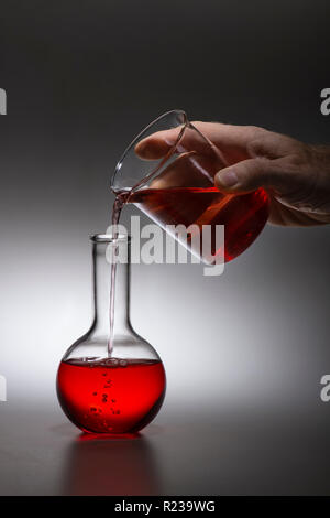 Hand Poring rote Flüssigkeit in der Chemie Experiment Stockfoto