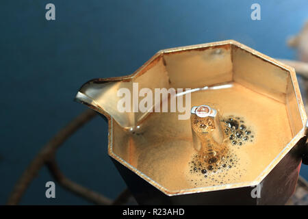 Der italienische Moka-Topf bereitet Kaffee zu, und das Getränk fängt an zu fließen. Stockfoto