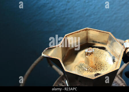 Der italienische Moka-Topf bereitet Kaffee zu, und das Getränk fängt an zu fließen. Stockfoto