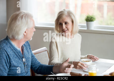 Gerne ältere Paare sprechen in der Küche in gesundes Frühstück zu Hause, älterer Mann und Frau genießen Sie leckeres Essen Zeit miteinander zu verbringen, alter Mann ein Stockfoto