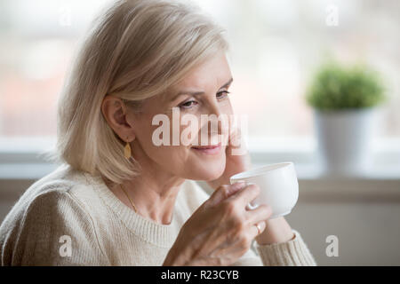 In der Nähe von schönen alten Frau trinkt Tee über angenehme Momente denken, nachdenklich älteren weiblichen Kaffeegenuss erinnern oder Träumen Stockfoto