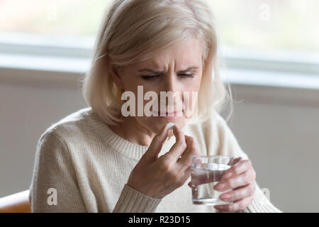 Nahaufnahme der gealterte Frau sich unwohl fühlen, Schmerzmittel oder Antibiotika Pille, älterer Frauen mit Depressionen Antidepressiva, ältere Dame halten Glas o Stockfoto