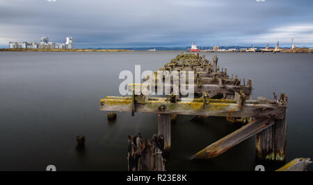 Edinburgh, Schottland, Großbritannien - 3. November 2018: Fracht- und Industrial Engineering ships Dock neben einem alten verfallenen und verlassenen hölzernen Pier in Edinburgh Stockfoto