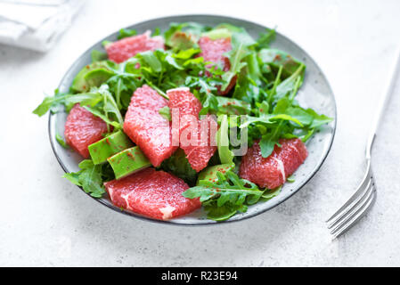 Rucola Salat mit Avocado, Grapefruit auf grauem Stein, kopieren. Gesunde vegane Ernährung grüner Salat mit Grapefruit, Avocado, Rucola und smo Stockfoto