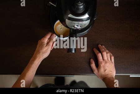Foto von Kaffeemaschine, Hände des Menschen Kaffee in der Tasse gießen Stockfoto