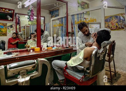 Indien, Himachal Pradesh, Manali: Ein Friseur schneidet einem Kunden in seinem Friseurladen einen Bart Stockfoto