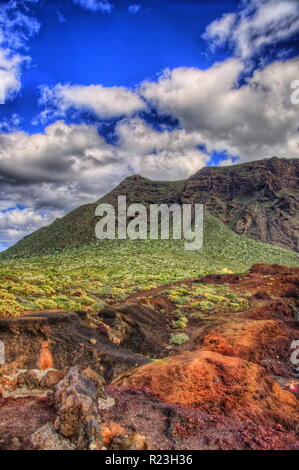 Wolken im blauen Himmel und grüne Felder mit Bergen an einem sonnigen Tag, Nordwestküste von Teneriffa in der Nähe von Punto Teno Leuchtturm, Canarias. Stockfoto