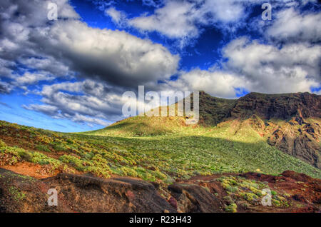 Wolken im blauen Himmel und grüne Felder mit Bergen an einem sonnigen Tag, Nordwestküste von Teneriffa in der Nähe von Punto Teno Leuchtturm, Canarias. Stockfoto