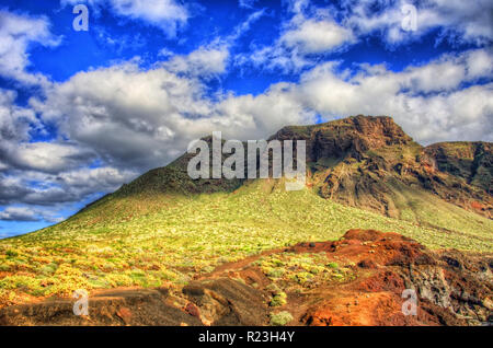 Wolken im blauen Himmel und grüne Felder mit Bergen an einem sonnigen Tag, Nordwestküste von Teneriffa in der Nähe von Punto Teno Leuchtturm, Canarias. Stockfoto