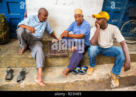 Drei lokale afrikanische Männer spielen traditionelle Brettspiel Mancala. Stone Town, alten kolonialen Zentrum von Zanzibar City, Unguja Insel, Tansania. Stockfoto