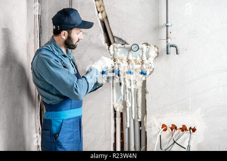 Arbeiter in der blauen Uniform Installation von Wasser- Heizung auf der Baustelle eines neuen Hauses Stockfoto