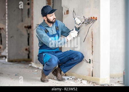 Den Kabelstrang der Halterung Elektriker für Steckdosen auf der Baustelle eines neuen Gebäudes im Innenbereich Stockfoto