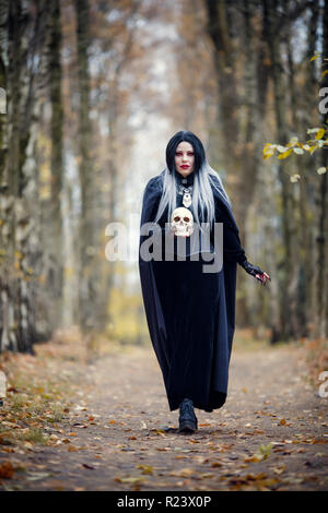 Portrait von Hexe Mädchen im vollen Wachstum im schwarzen Mantel mit Schädel Stockfoto