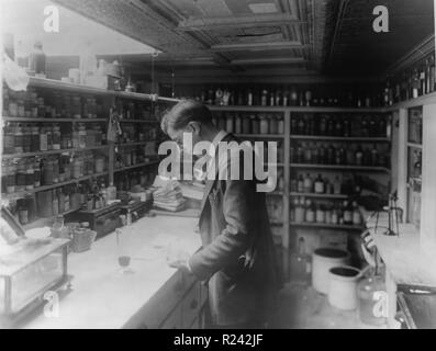 Apotheker in Volksrepublik Drogerie, 8. und H Street, N.E., Washington, D.C., mit Blick auf Rezepte auf der Theke, im Raum mit Regalen Apotheke Flaschen 1920 Stockfoto