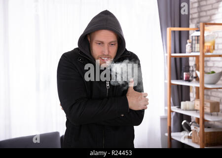 Porträt eines jungen Mannes aus dem Kalten Ausatmen Einatmen zu Hause Leiden Stockfoto