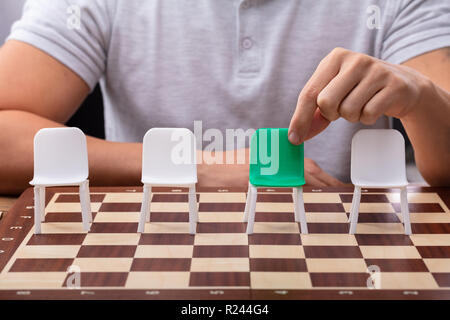 Des Menschen Hand Sie grünen Stuhl unter Anderem auf Schachbrett Stockfoto