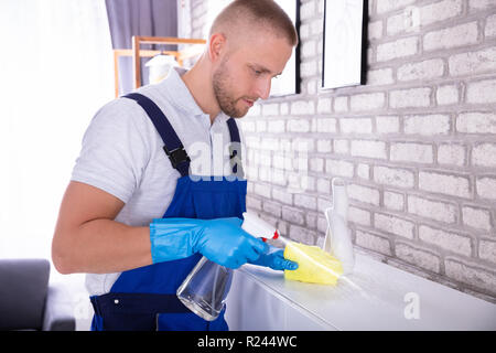 Nahaufnahme eines jungen männlichen Hausmeister Reinigung Möbel mit gelben Tuch Stockfoto