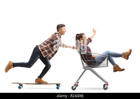 Volle Länge geschossen von einem jungen Kerl reiten ein Longboard drücken ein Mädchen in einem Warenkorb auf weißem Hintergrund Stockfoto