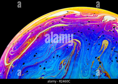 Nahaufnahme Regenbogen Farben in einer Seifenblase, wie Leerzeichen oder Planeten oder Welten auf einem schwarzen Hintergrund isoliert betrachten Stockfoto