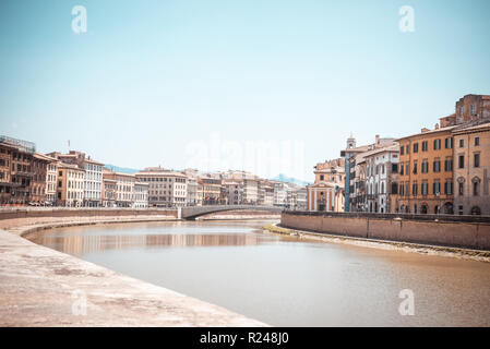 Horizontale Foto mit Blick auf den Fluss Arno, die durch die berühmten Stadt Pisa in Italien Toskana geht. Wasser ist braun. Gebäude sind auf beiden Seiten. Hügel sind im Hinterg Stockfoto