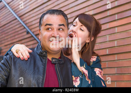 Kaukasische Frau Whispering Geheimnis Hispanic Man. Stockfoto