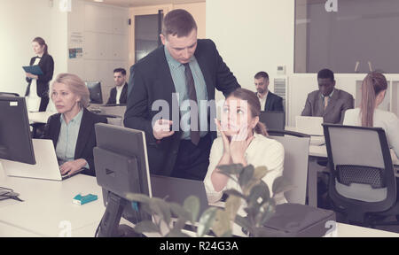 Empört Manager der Unzufriedenheit mit der Arbeit der frustrierten jungen Frau in modernen Büro Stockfoto
