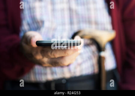 Nahaufnahme von einem alten kaukasischen Mann mit einem smartphone Stockfoto