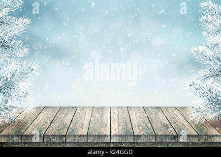 Leere Holztisch und Weihnachten Tanne mit Schnee bedeckt. Schnee fällt. Blauen Hintergrund. Stockfoto