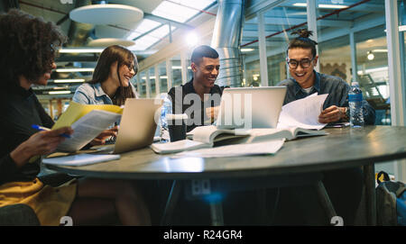 Glückliche junge Studenten studieren mit Bücher und Laptops in der Bibliothek. Gruppe der multirassischen Menschen in der Hochschule Bibliothek. Stockfoto