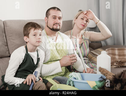 Müde Eltern mit Sohn für die Reinigung auf der Couch zu Hause ruhenden gekleidet Stockfoto