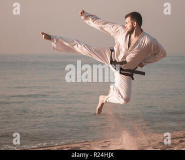 Positiver Mann tun Karate im Ocean Quay in der Dämmerung Stockfoto