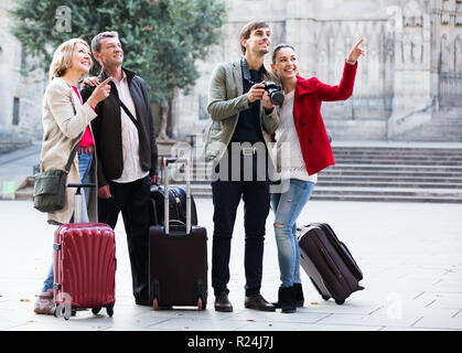 Gruppe von Touristen in ungezwungener Atmosphäre mit Gepäck Spaziergang entlang der Straßen im Außenbereich. Fokus auf reifer Mann Stockfoto