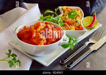 Hühnereintopf mit Ananas und Chili Tomatensauce in einer weißen Schüssel serviert mit gekochten Reis mit Gemüse. Gesunde Ernährung Konzept Stockfoto