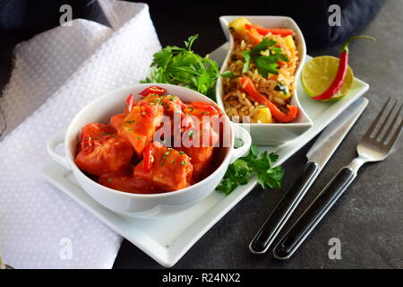 Hühnereintopf mit Ananas und Chili Tomatensauce in einer weißen Schüssel serviert mit gekochten Reis mit Gemüse. Gesunde Ernährung Konzept Stockfoto