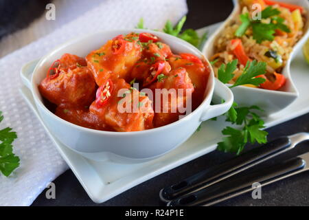 Hühnereintopf mit Ananas und Chili Tomatensauce in einer weißen Schüssel serviert mit gekochten Reis mit Gemüse. Gesunde Ernährung Konzept Stockfoto